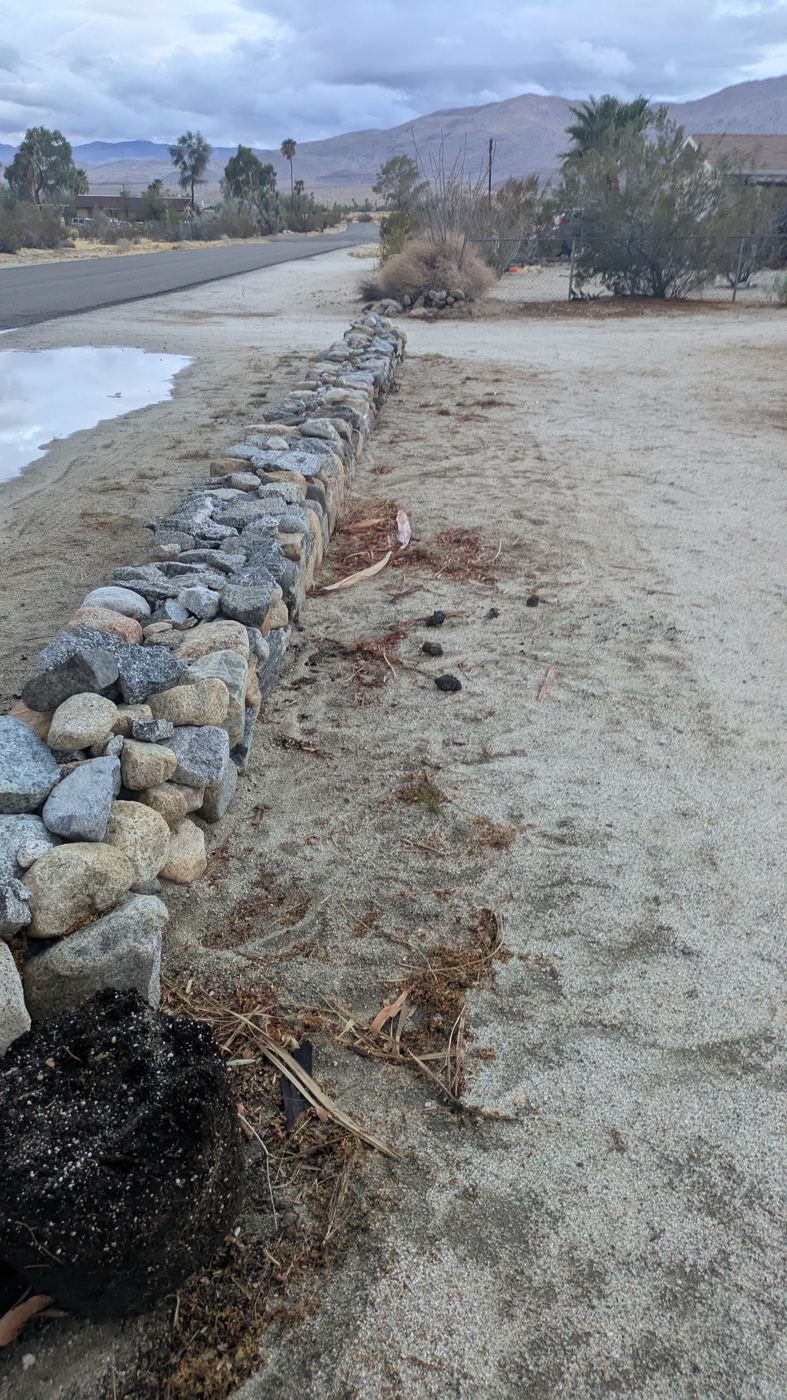 Dry-stacked rock berm at Ark Unit 1 with mulch on the yard side