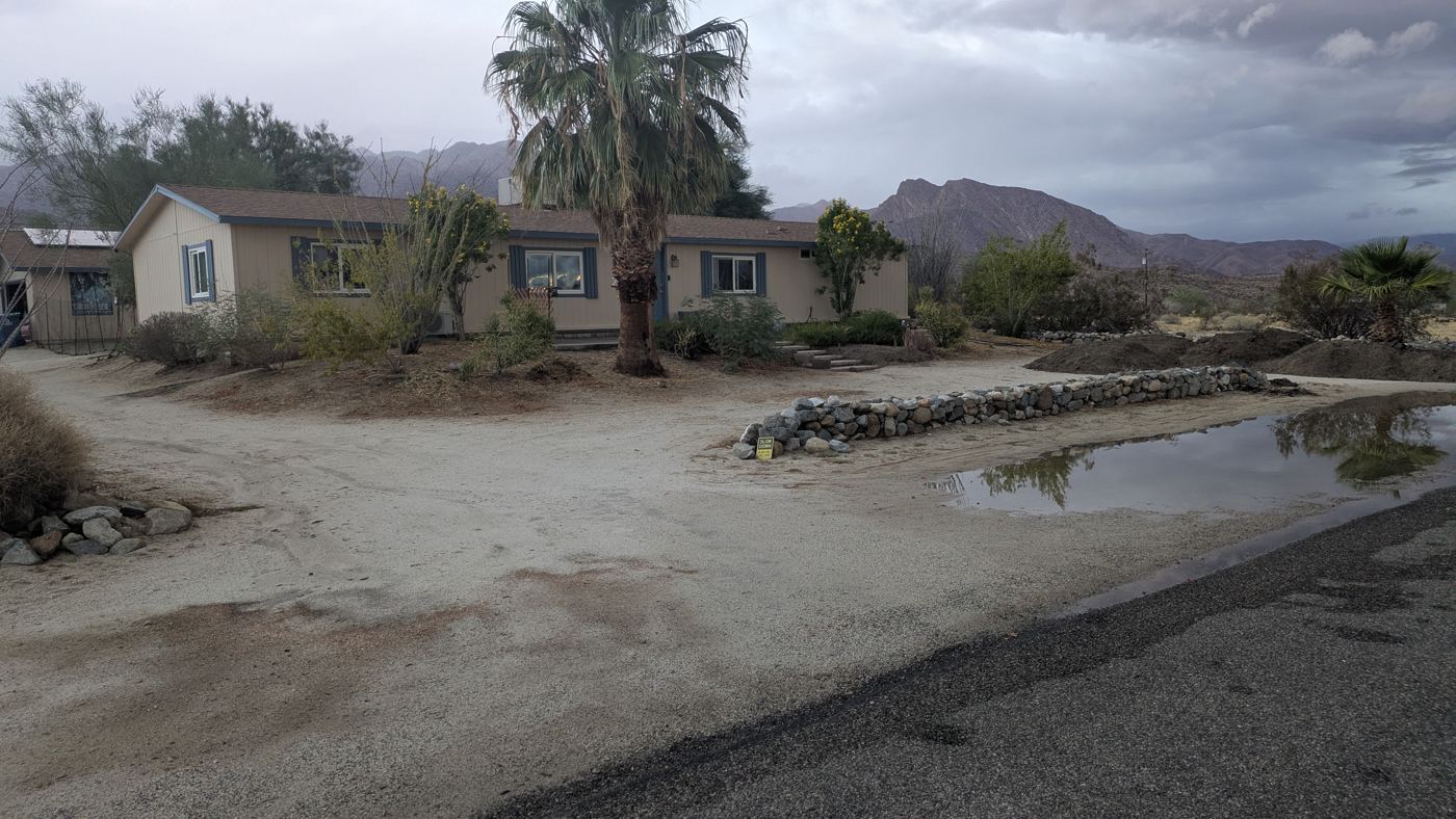 Storm water pooled on the road side of the berm while the yard behind it has no standing water